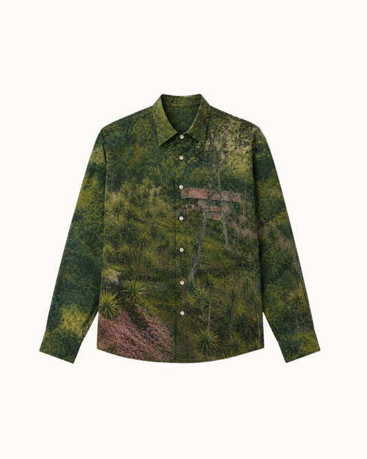 A long-sleeve button-up shirt featuring an all-over scenic print of a lush green forest with a torii gate, displayed on a clean off-white background.