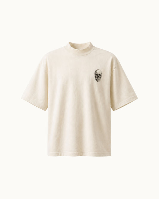 An off-white short-sleeve t-shirt with a mock neck and a small black skull graphic on the left chest, displayed against a solid off-white background.